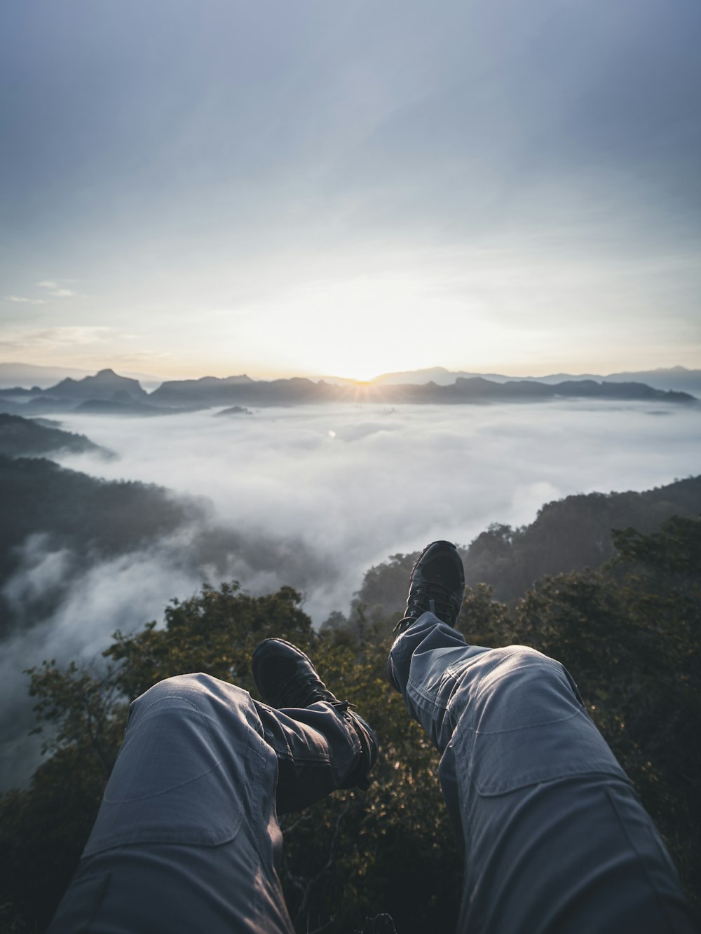 person's feet facing foggy mountain field during golden hour