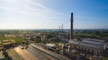 A panoramic view of the Trombay production unit with chimneys and industrial structures under a clear sky.