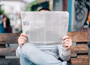 man sitting on bench reading newspaper