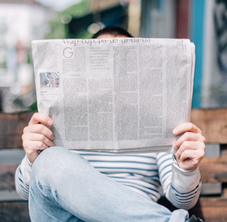 man sitting on bench reading newspaper