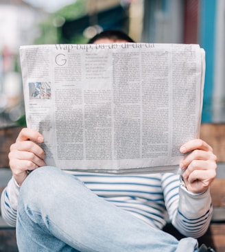 man sitting on bench reading newspaper