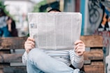 man sitting on bench reading newspaper