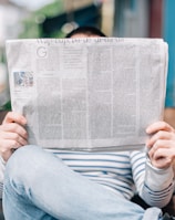 man sitting on bench reading newspaper