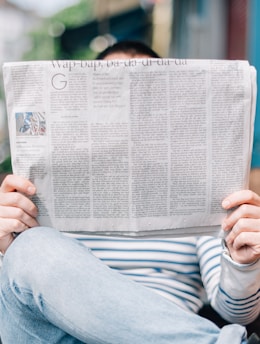 man sitting on bench reading newspaper