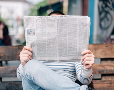 man sitting on bench reading newspaper