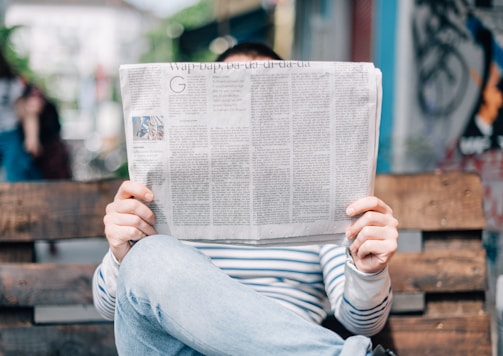 man sitting on bench reading newspaper