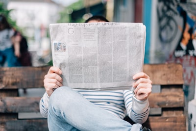 man sitting on bench reading newspaper read google meet background