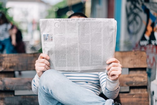 Imagem do homem lendo jornais, como as notícias da indústria que podem servir de conteúdo útil