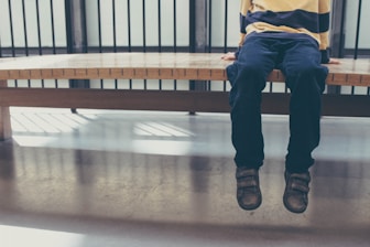 enfant seul inquiet assis sur un banc