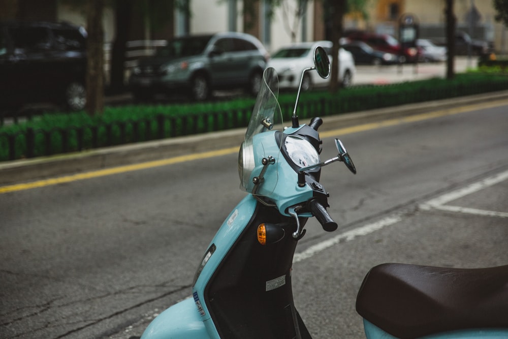 blue motor scooter parked beside road