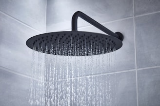 High-tech showerhead releasing a gentle cascade of water in a bright, stylish bathroom.