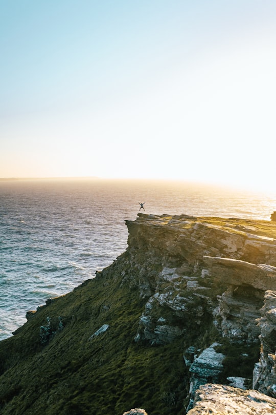 man jumping on cliff in Tintagel United Kingdom