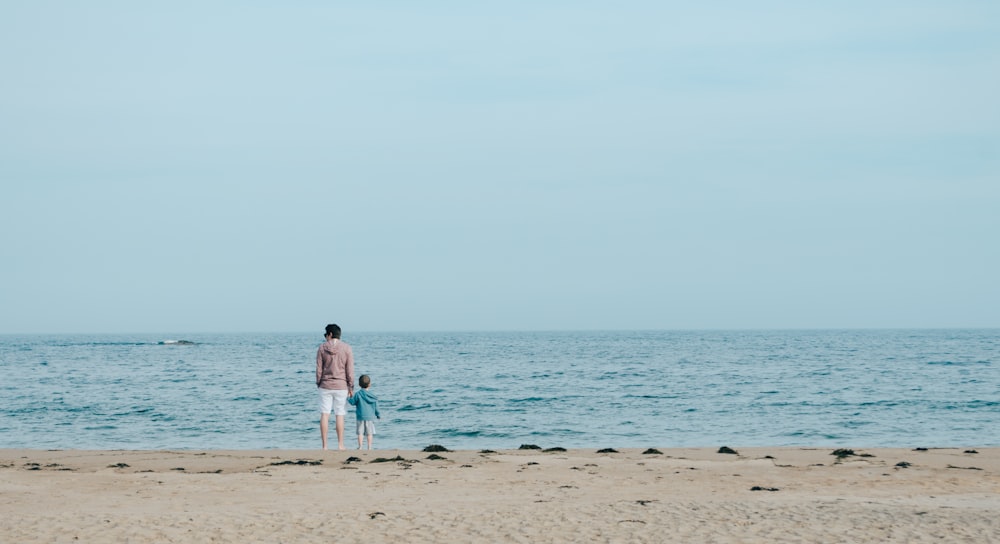 homem e criança em pé na praia