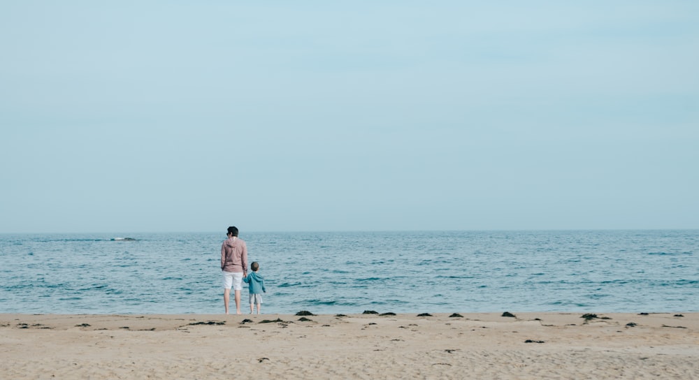 man and toddler standing on shore