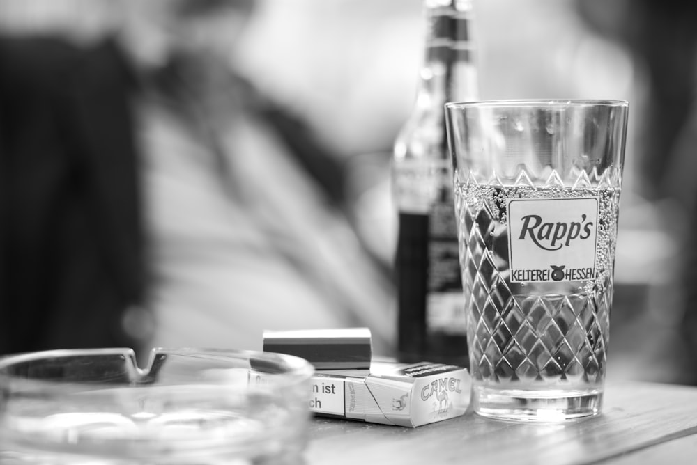 grayscale photo of glass cup on table