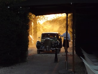A faded but cared-for estate car parked alongside a quiet countryside lane, morning fog lifting.