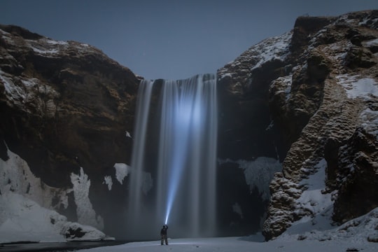 man standing in front of the waterfalls in Skógafoss Iceland