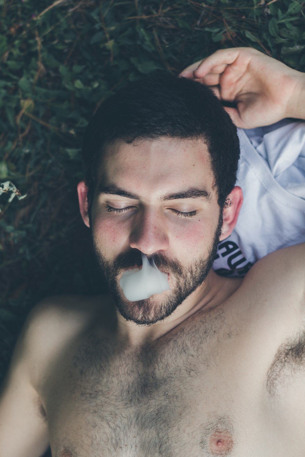 man lying on grass field while smoking
