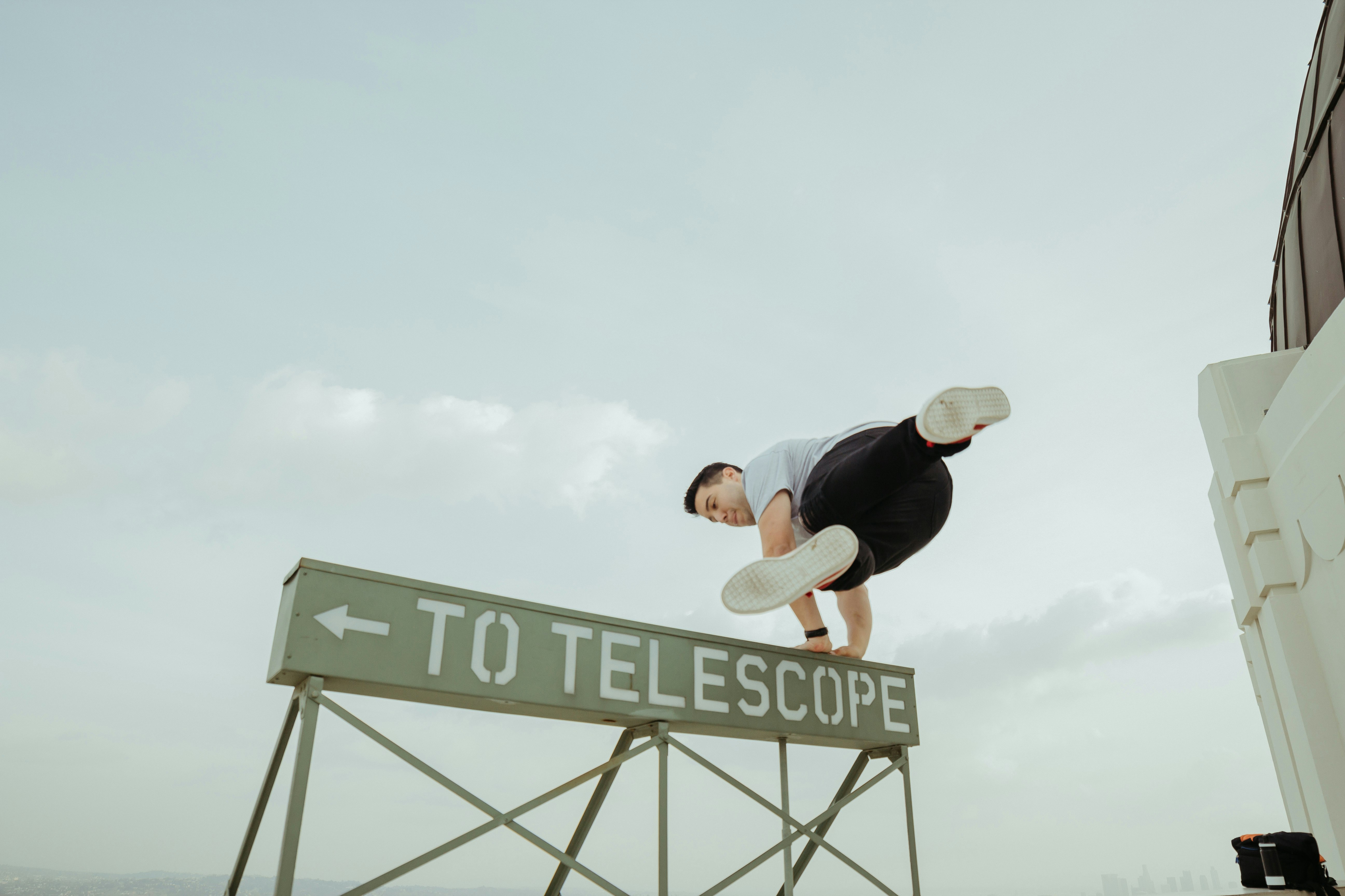 man jumping over to telescope signage
