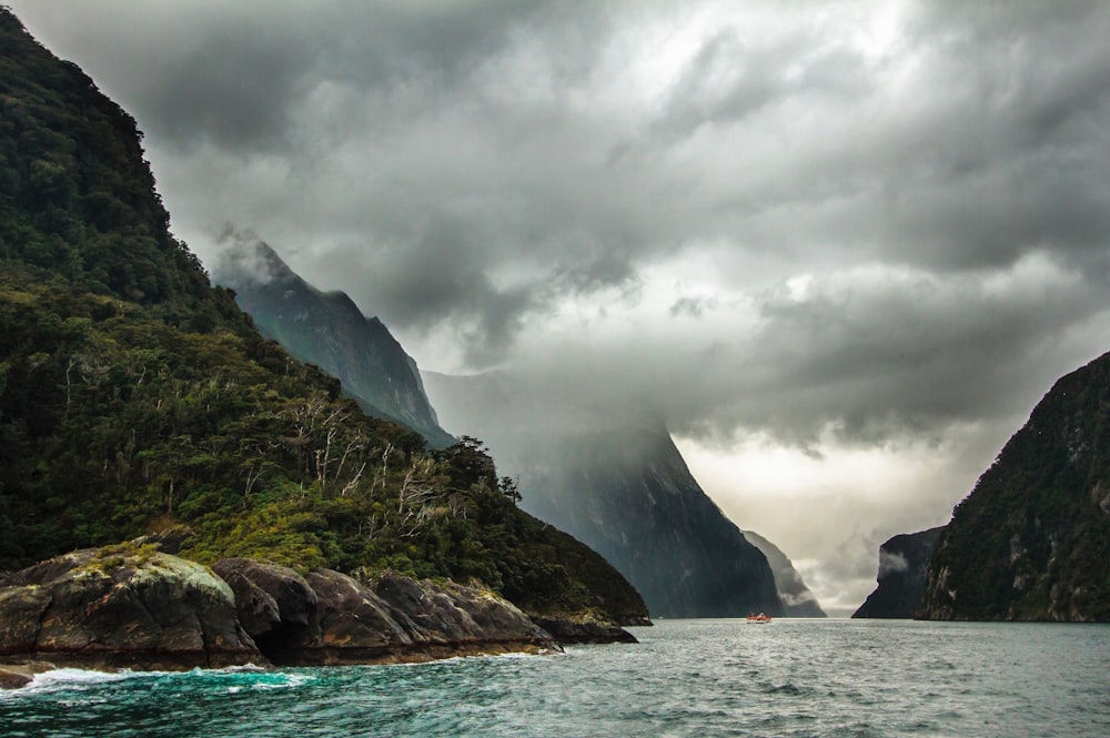 peak of mountain covered with clouds near body of water