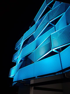 A sleek adaptive façade lighting system illuminating a modern corporate building with dynamic electric blue hues.
