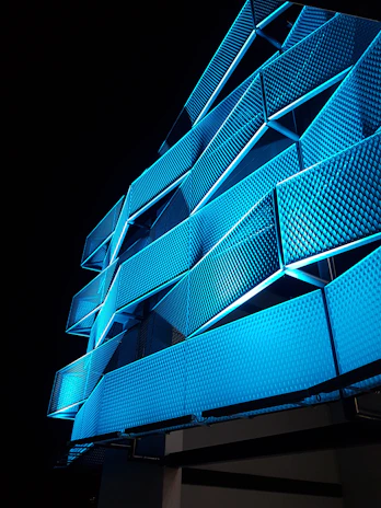 A sleek adaptive façade lighting system illuminating a modern corporate building with dynamic electric blue hues.