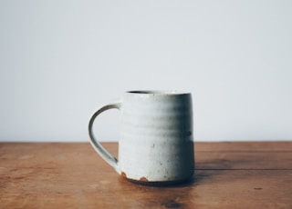 white ceramic mug on wooden table top