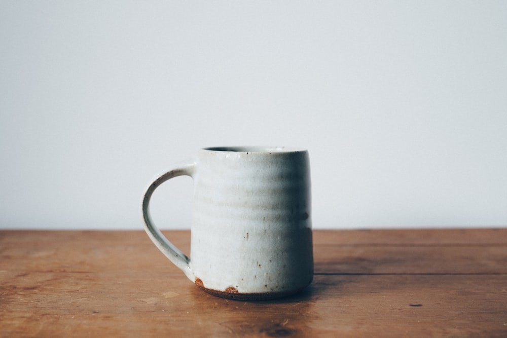 white ceramic mug on wooden table top