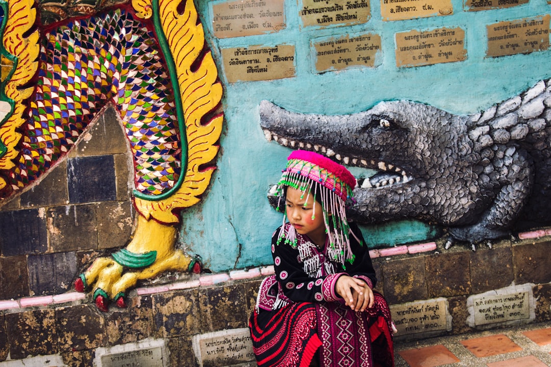 girl wearing multicolored traditional dress sitting near the wall