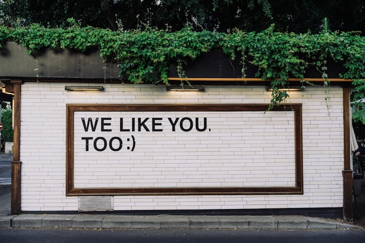 A wall with text reading "WE LIKE YOU TOO :)"