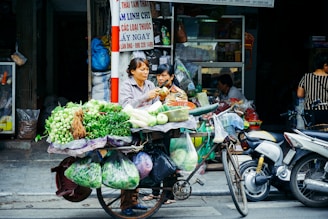 woman slicing vegetable on her bike stand near store