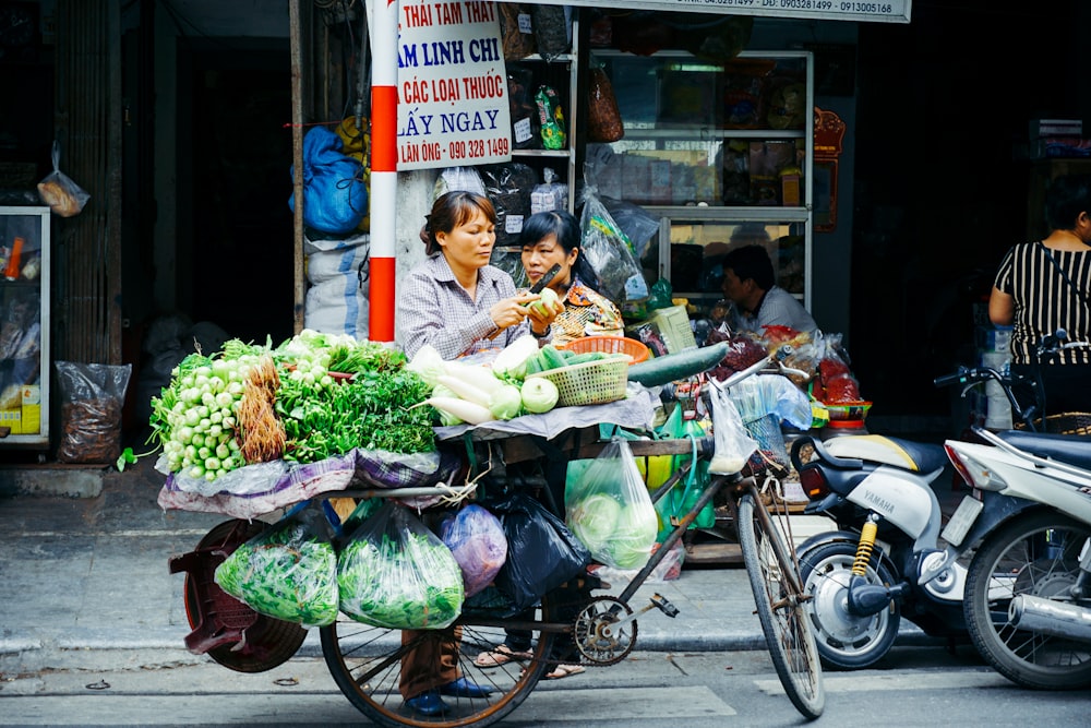 Frau schneidet Gemüse auf ihrem Fahrradständer in der Nähe des Ladens