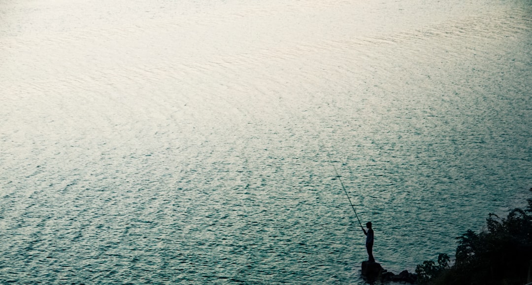 person stand on rock near body of water during daytime