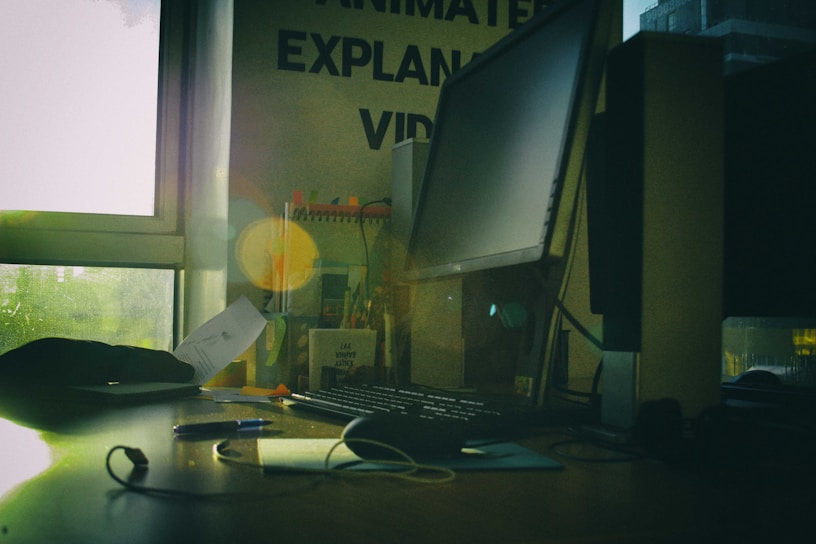 A warmly lit office space with stacks of research papers and a laptop open on a wooden desk.