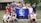 A group of young people gathered together outdoors in front of a building, holding a blue flag with the Earth on it and the words 'PHS Global Ecology.' The group appears cheerful and diverse, standing closely together.
