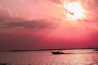 A high-performance boat speeding across waves with a vibrant sunset in the background.