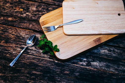 stainless steel spoon and fork on brown wooden board