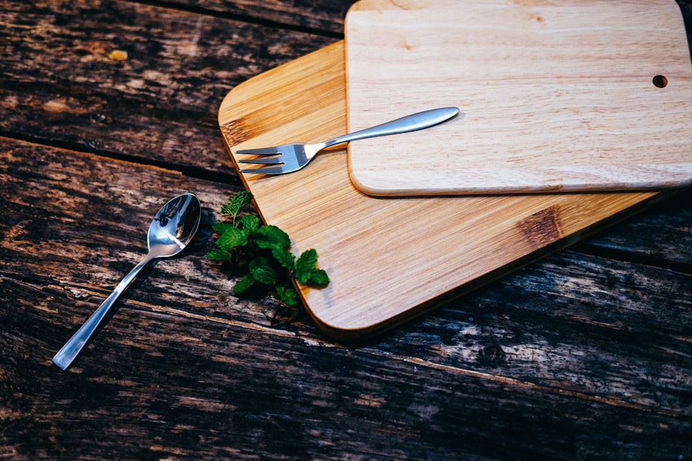 stainless steel spoon and fork on brown wooden board