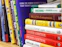 A collection of business and motivational books on a shelf, featuring titles like 'Greening Your Business,' 'Billions of Entrepreneurs,' 'Great Again,' and 'Higher Ambition.' The books are arranged vertically, showing a variety of colors and sizes.