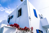 Exterior of a Houston home with a vibrant blue facade and perfectly painted white shutters under a clear sky.