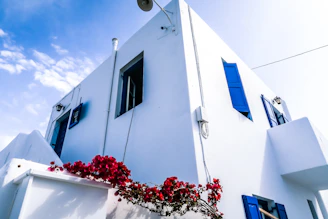 Exterior of a Houston home with a vibrant blue facade and perfectly painted white shutters under a clear sky.