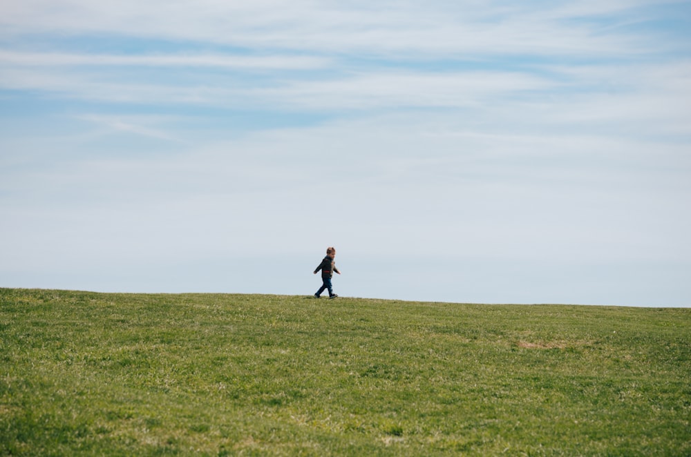 bambino che cammina sul campo di erba verde