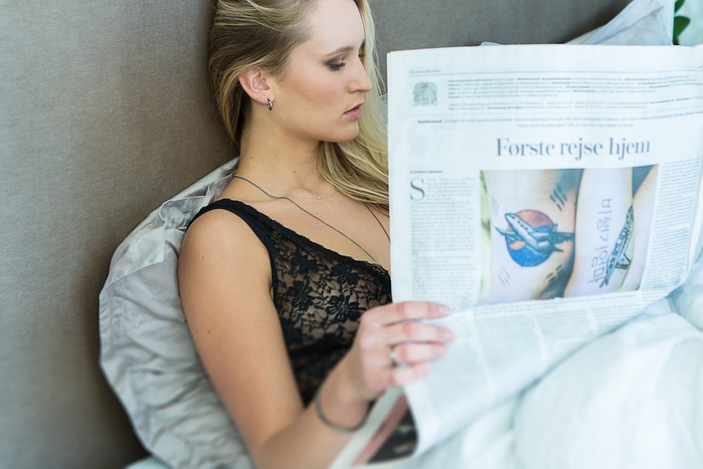 femme portant une chemise noire lisant le journal