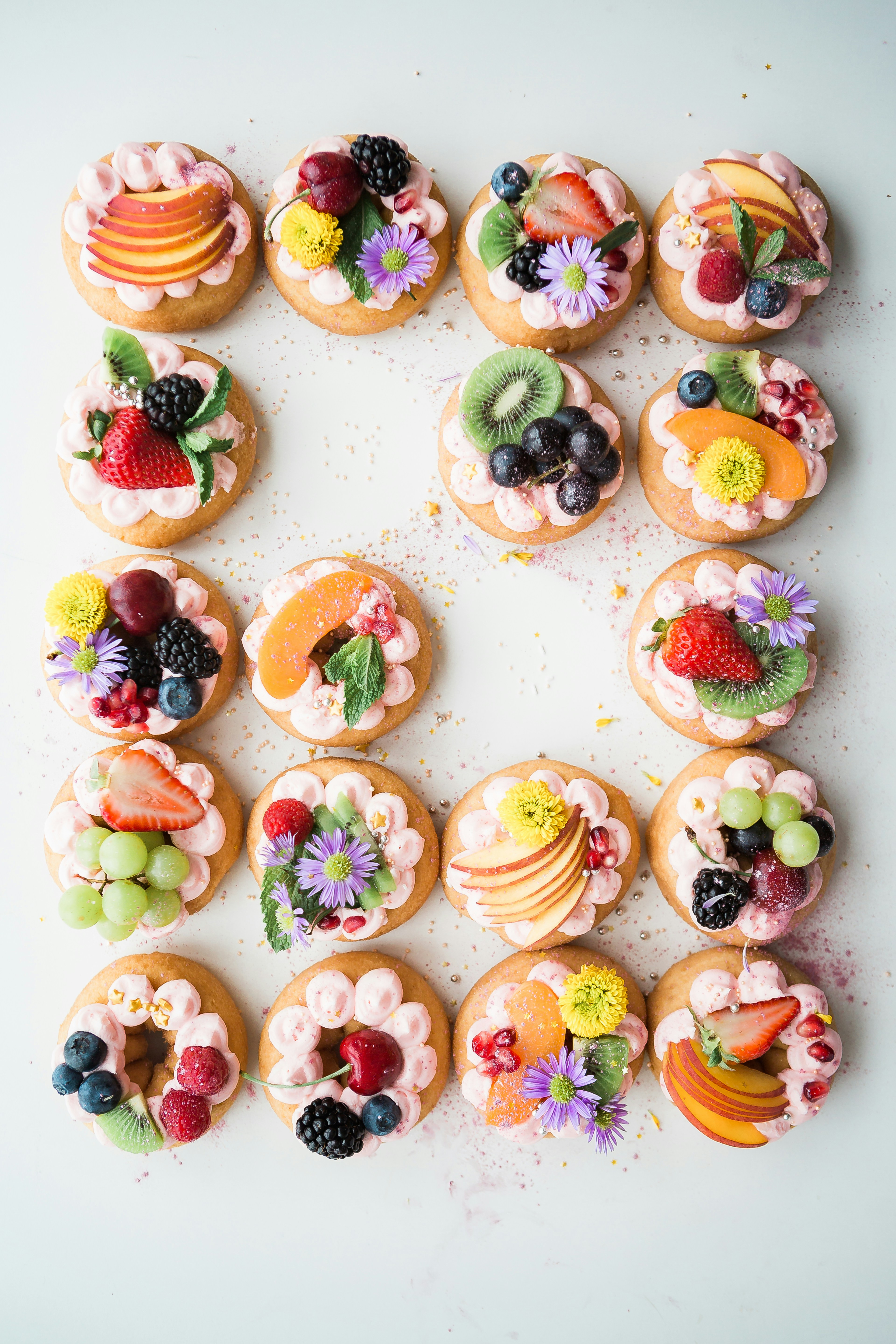 Eco-friendly wedding desserts topped with fresh fruit and edible flowers on mini cakes.