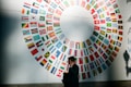 woman in black coat standing near round white red and blue wall