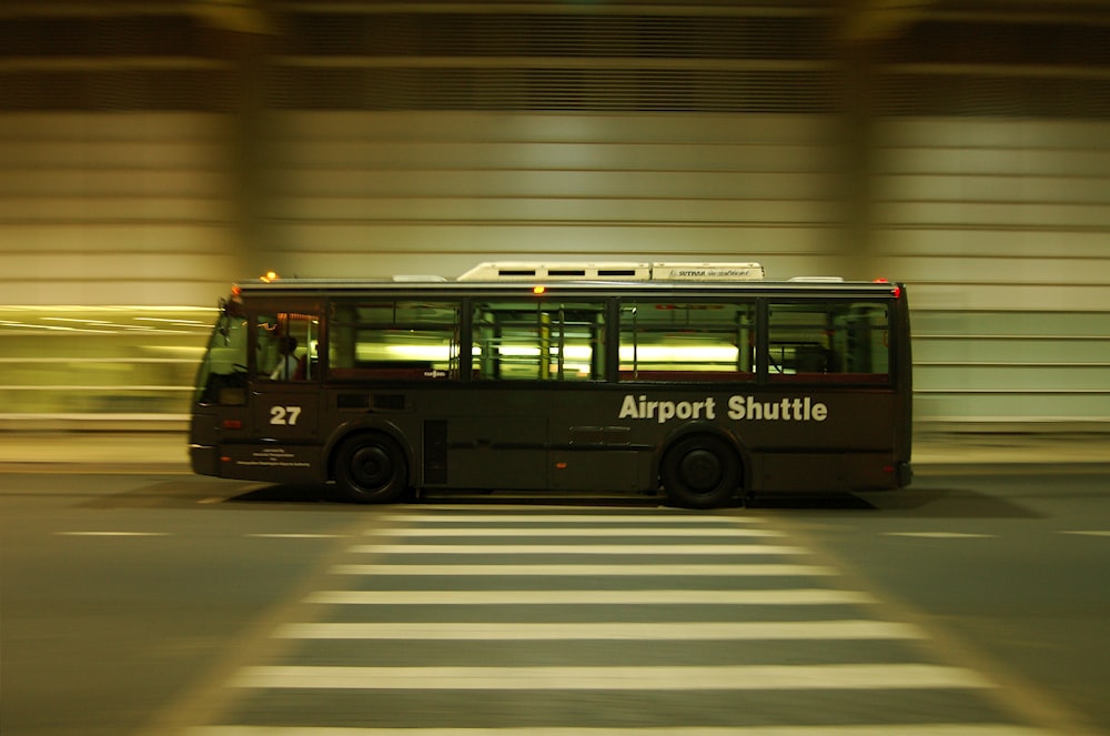 灰色の道路を走る赤と黒のバス