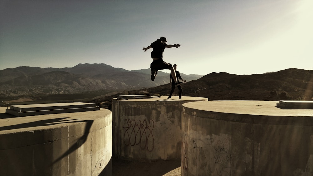 man jumping between two cylinder buldings