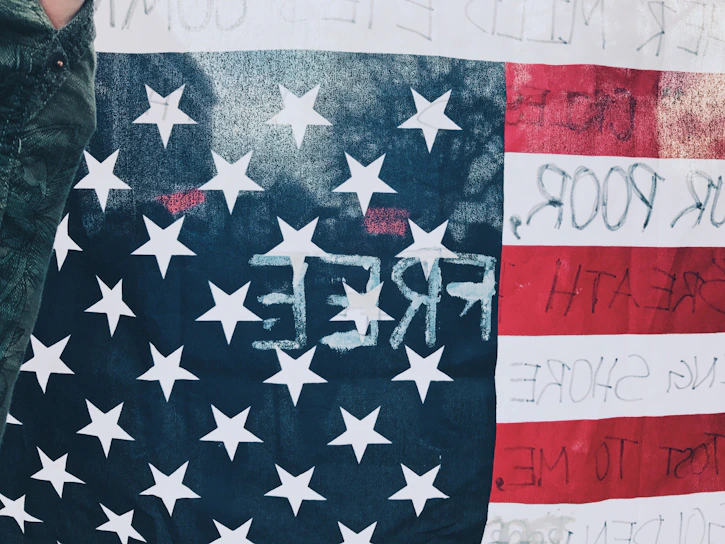 Close-up of a black t-shirt with a bold red and white patriotic slogan in military stencil font.
