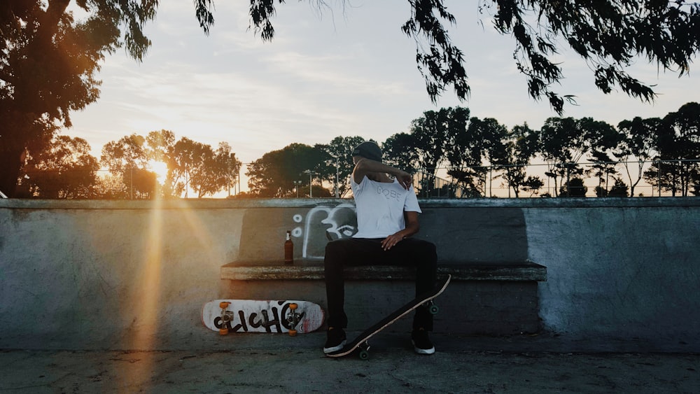 homme assis sur une chaise à côté d’une planche à roulettes blanche