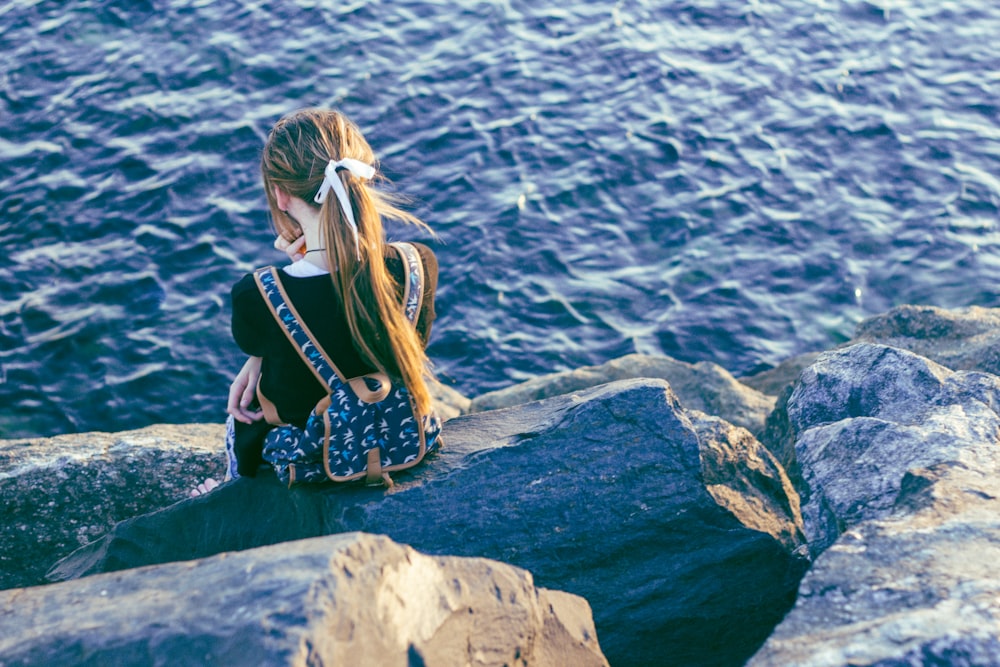 fille assise sur des rochers gris